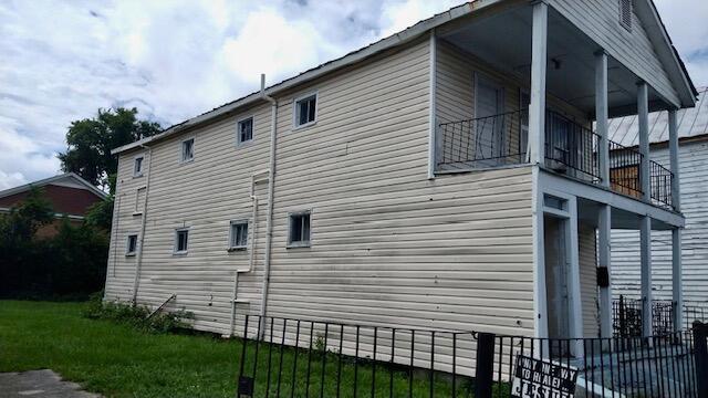 view of side of property featuring a balcony and a lawn