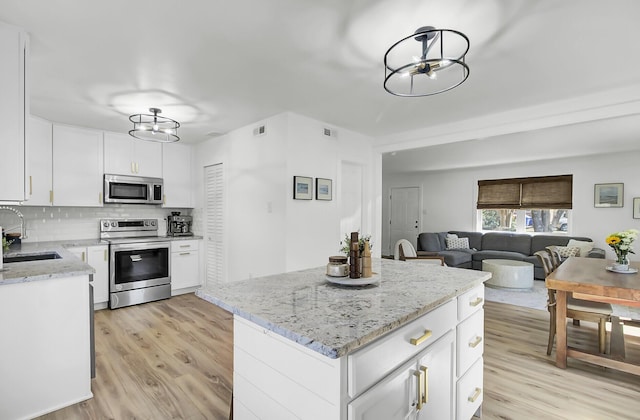 kitchen with light wood-type flooring, tasteful backsplash, stainless steel appliances, and a sink