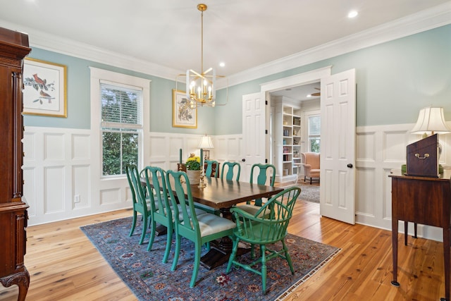 dining room with a decorative wall, plenty of natural light, wainscoting, a chandelier, and ornamental molding