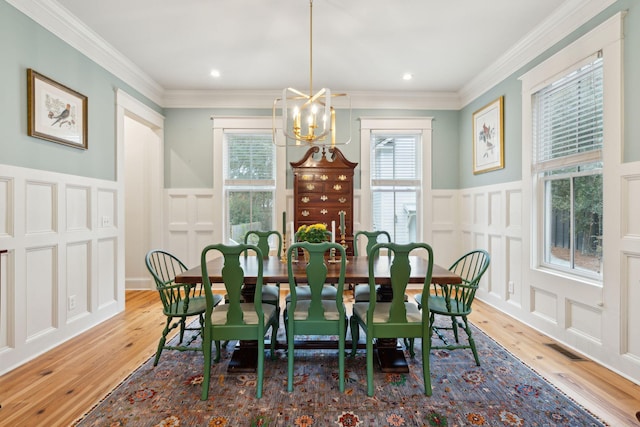 dining room with visible vents, a decorative wall, light wood finished floors, and an inviting chandelier