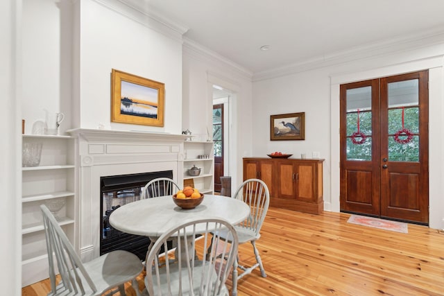 dining area with a fireplace, light wood-style flooring, crown molding, and baseboards