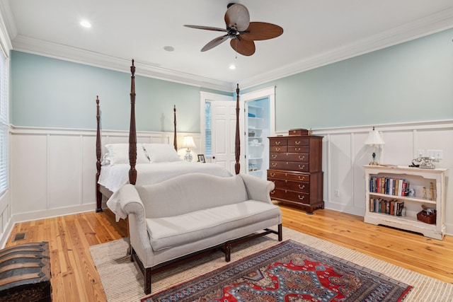 bedroom with a wainscoted wall, light wood-style floors, and a decorative wall