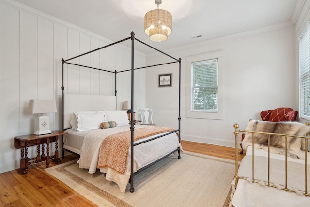 bedroom with light wood-type flooring, visible vents, and ornamental molding