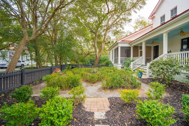 view of yard featuring fence, a porch, and a ceiling fan