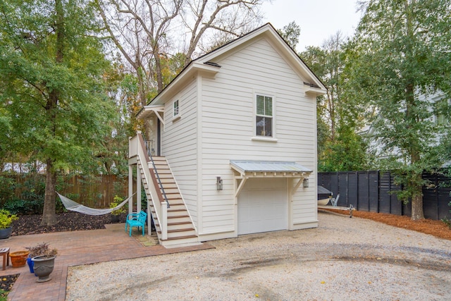 exterior space with fence, an attached garage, driveway, and stairs