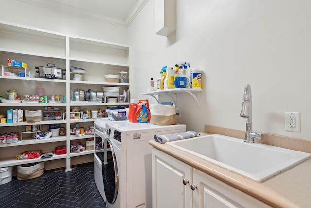 laundry area with washing machine and clothes dryer, a sink, cabinet space, ornamental molding, and dark tile patterned floors