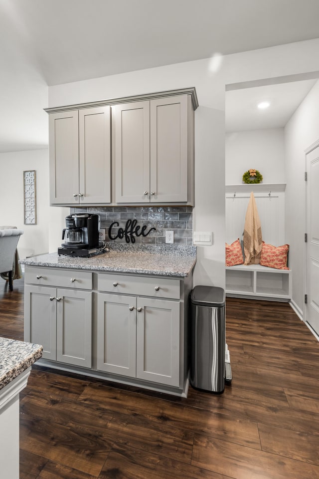 kitchen with light stone counters, dark wood-type flooring, tasteful backsplash, and gray cabinetry