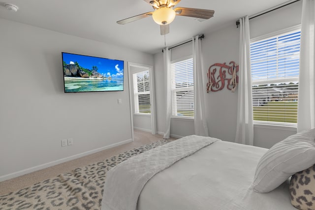 bedroom with ceiling fan, light colored carpet, and multiple windows