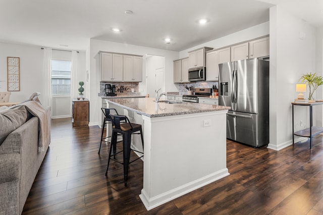 kitchen featuring appliances with stainless steel finishes, gray cabinets, dark hardwood / wood-style flooring, and an island with sink