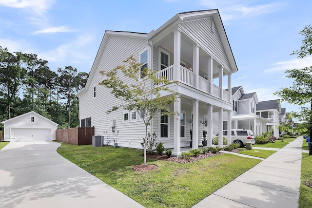 view of property exterior featuring a balcony, an outbuilding, a detached garage, a yard, and a porch
