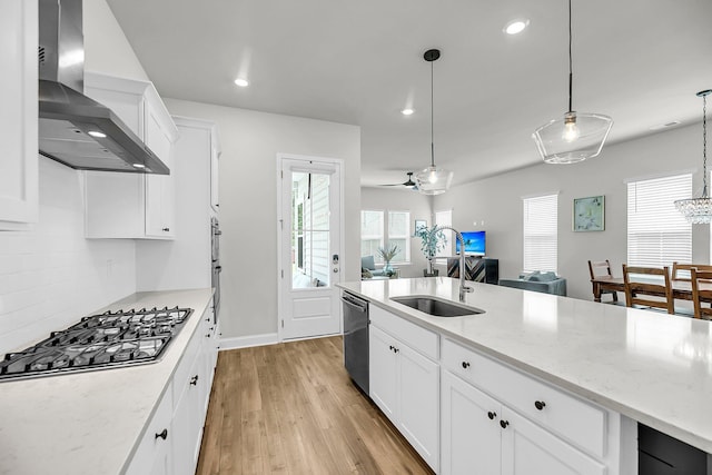 kitchen with wall chimney range hood, appliances with stainless steel finishes, a sink, light wood-type flooring, and recessed lighting