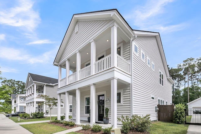 view of front facade featuring a balcony, a porch, and fence