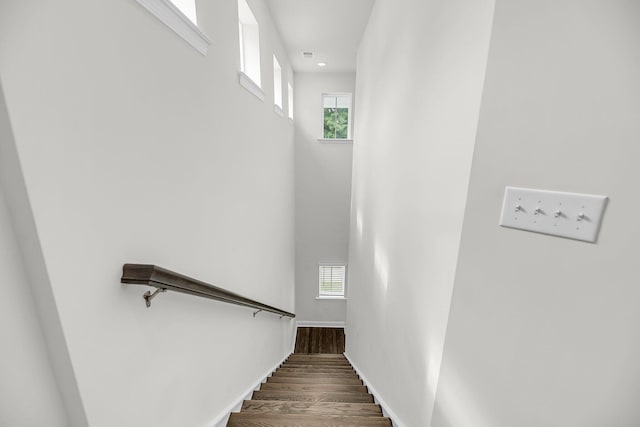 staircase with wood finished floors, baseboards, and recessed lighting