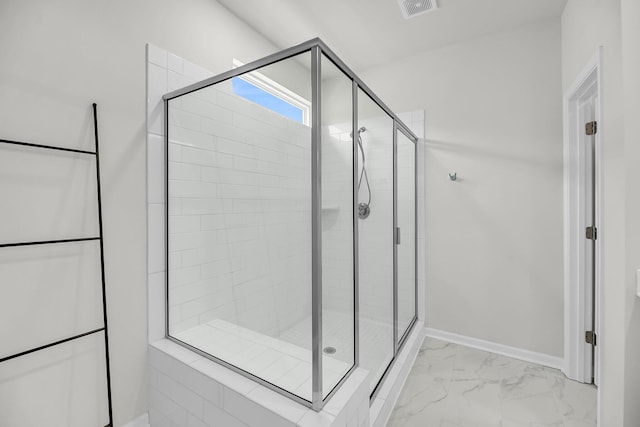 bathroom with a stall shower, marble finish flooring, and baseboards