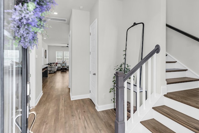 foyer featuring wood finished floors, stairway, baseboards, and ceiling fan