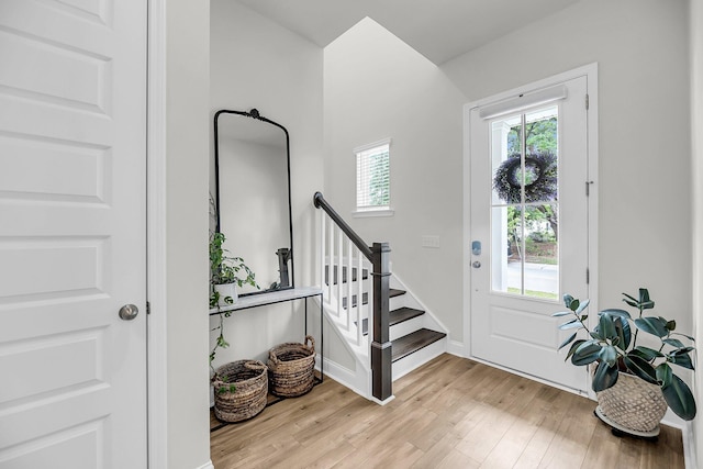 foyer entrance with plenty of natural light, wood finished floors, stairway, and baseboards