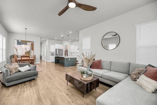 living room with a chandelier, light wood finished floors, ceiling fan, and recessed lighting