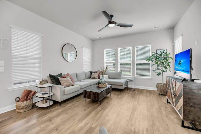 living area featuring a ceiling fan, baseboards, and light wood-style floors
