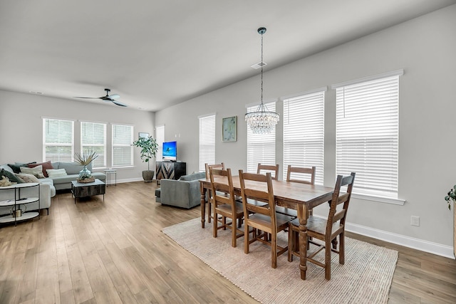 dining space featuring a chandelier, wood finished floors, baseboards, and a ceiling fan
