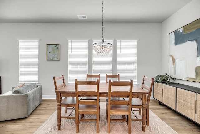 dining space featuring a chandelier, light wood-style floors, and baseboards