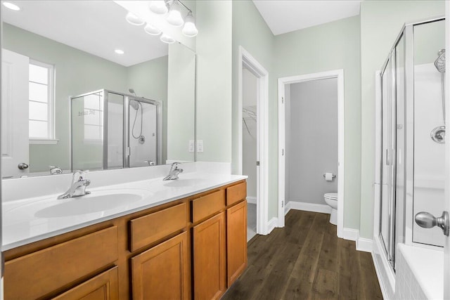 bathroom featuring vanity, hardwood / wood-style flooring, toilet, and a shower with door