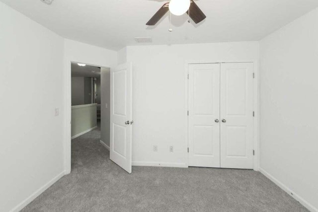 unfurnished bedroom with ceiling fan, a closet, and light carpet