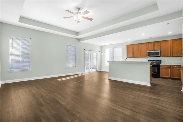 kitchen with dark wood-type flooring, a raised ceiling, black electric range, decorative light fixtures, and a kitchen island