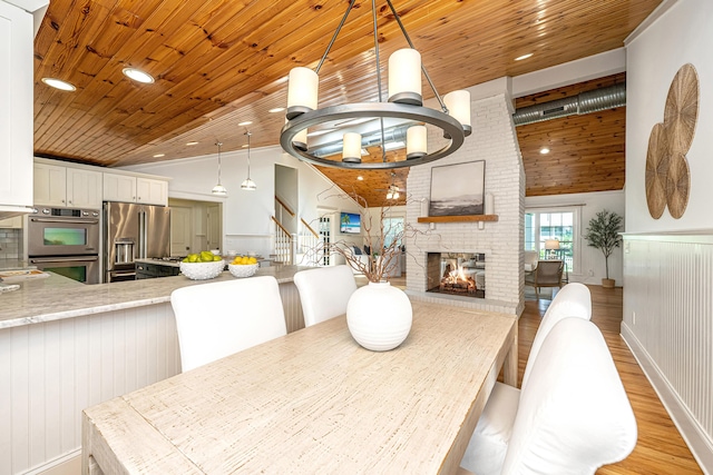 3002 Waterway Blvd, Isle Of Palms, SC 29451 - dining space with light wood-style flooring, wood ceiling, stairway, a brick fireplace, and a chandelier