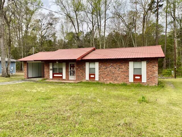 1806 S Charleston Ave, Fairfax, SC 29827 - view of front of home featuring metal roof, a front lawn, brick siding, and a carport