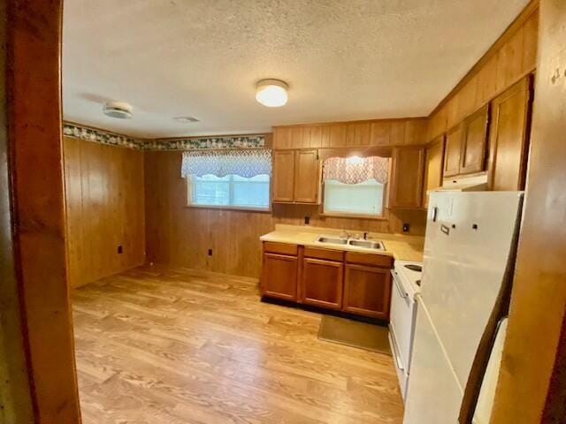 1806 S Charleston Ave, Fairfax, SC 29827 - kitchen featuring light wood-type flooring, a textured ceiling, a sink, wooden walls, and brown cabinetry