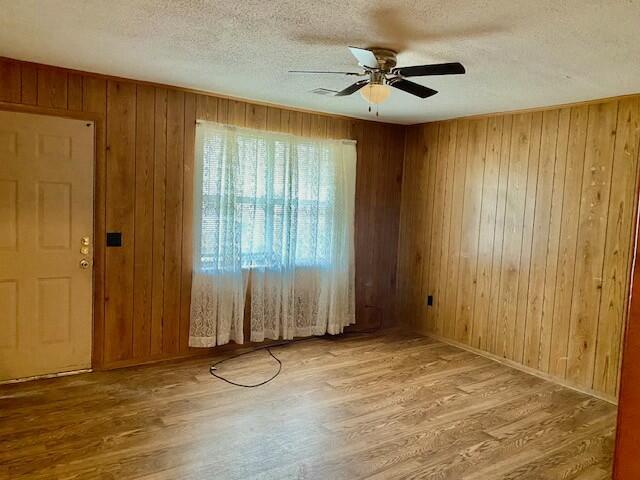 1806 S Charleston Ave, Fairfax, SC 29827 - empty room with a textured ceiling, wood finished floors, a ceiling fan, and wood walls