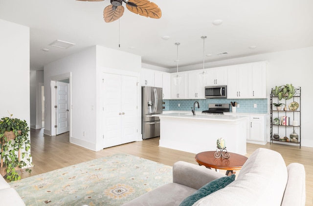 living room with ceiling fan, light wood-type flooring, and sink