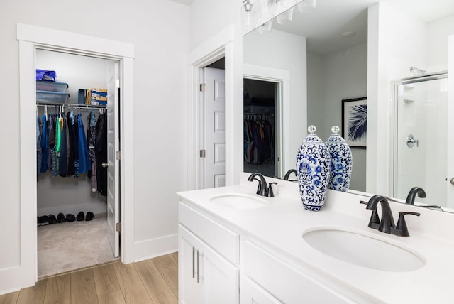 bathroom featuring wood-type flooring, a shower with door, and vanity