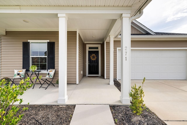 view of exterior entry featuring a garage and covered porch