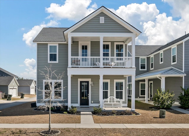 view of front facade featuring a balcony, covered porch, and a shingled roof