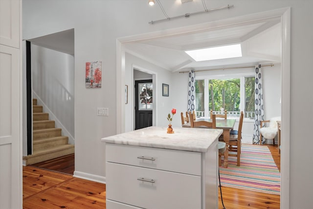 kitchen with light stone counters, hardwood / wood-style floors, and white cabinetry