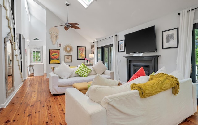 living room featuring high vaulted ceiling, light wood-type flooring, and ceiling fan