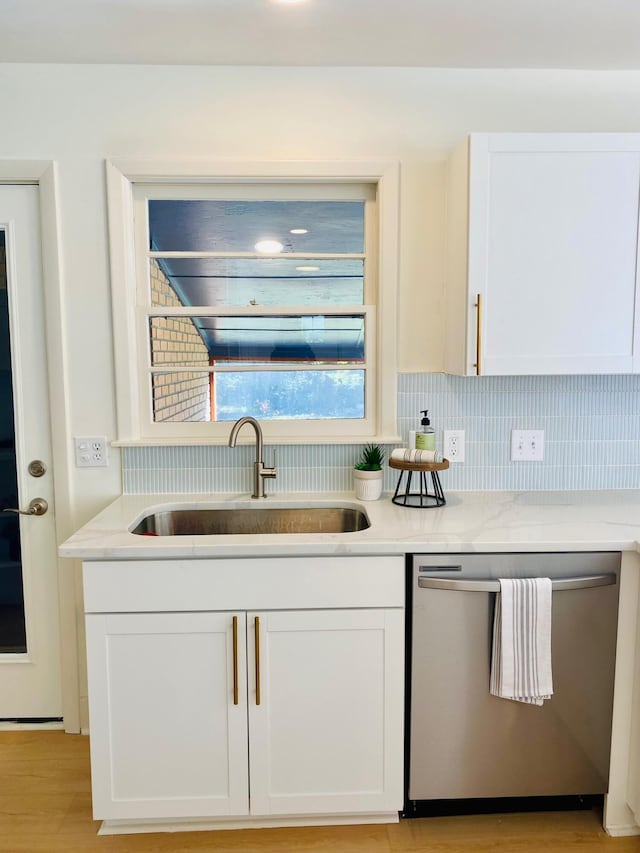 kitchen featuring decorative backsplash, dishwasher, white cabinets, and sink