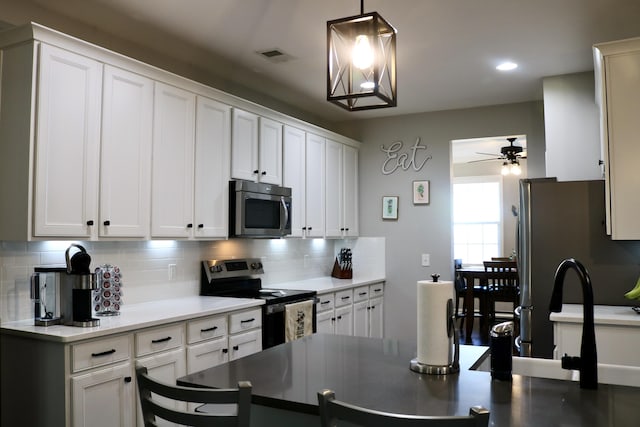 kitchen with pendant lighting, decorative backsplash, white cabinetry, appliances with stainless steel finishes, and ceiling fan