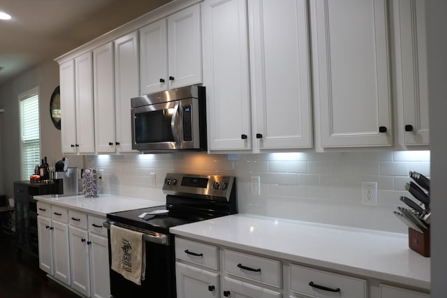 kitchen featuring appliances with stainless steel finishes, backsplash, and white cabinetry