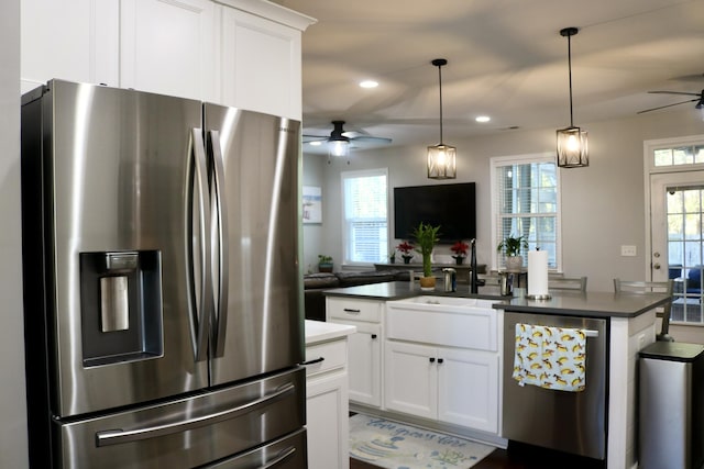 kitchen featuring stainless steel appliances, a kitchen island, white cabinets, decorative light fixtures, and sink