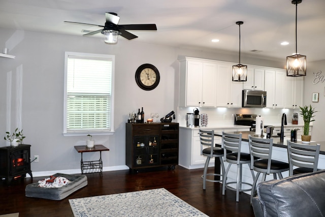 kitchen with stainless steel appliances, white cabinetry, decorative backsplash, hanging light fixtures, and dark hardwood / wood-style flooring