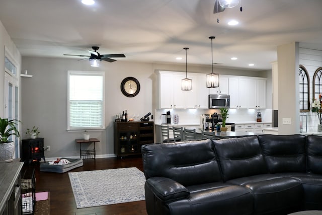 living room with ceiling fan and dark wood-type flooring