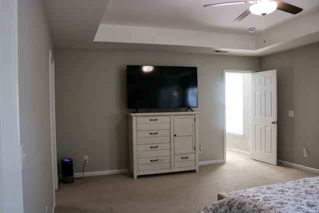 carpeted bedroom featuring a raised ceiling and ceiling fan