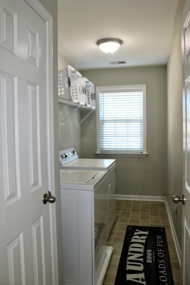 clothes washing area featuring washing machine and clothes dryer and dark tile patterned flooring