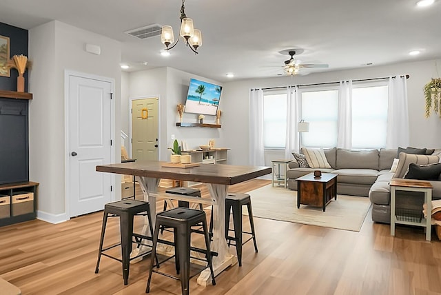 dining space featuring recessed lighting, ceiling fan with notable chandelier, visible vents, baseboards, and light wood-type flooring