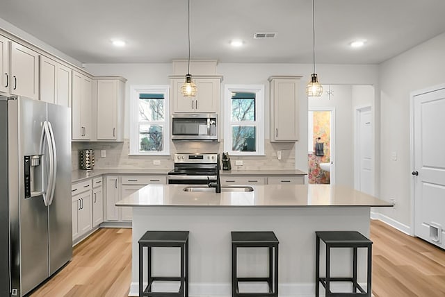 kitchen featuring light wood-type flooring, visible vents, appliances with stainless steel finishes, and a breakfast bar