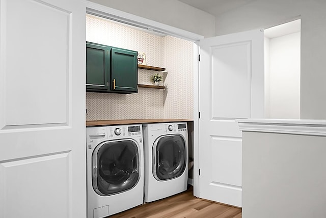 clothes washing area featuring light wood-type flooring, washing machine and clothes dryer, and cabinet space