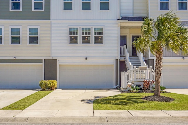 townhome / multi-family property featuring a garage, concrete driveway, and stairway