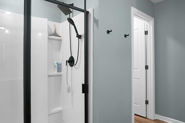 full bath with wood finished floors, a shower stall, and baseboards